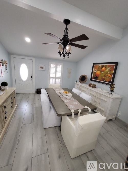 A dining room with a table set for four and a painting on the wall.