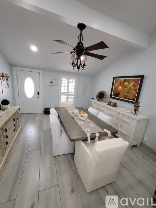A dining room with a table set for four and a painting on the wall.
