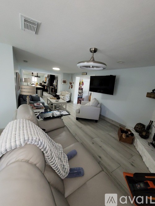 A living room with a grey couch and a television on the wall.