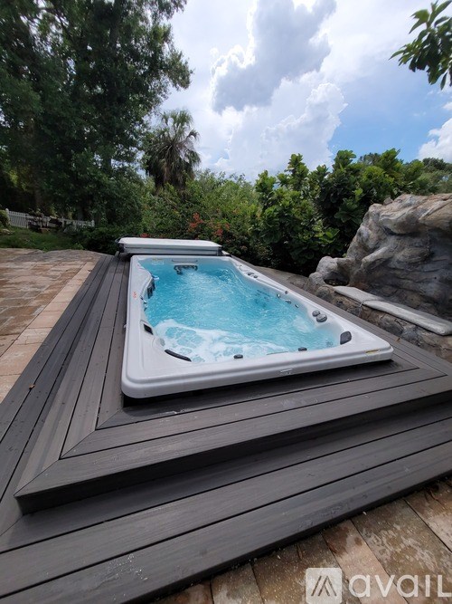 A hot tub sits on a wooden deck with trees in the background.