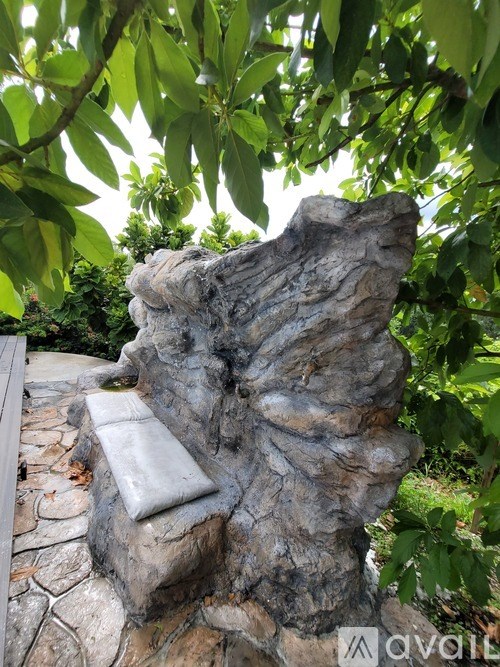 A stone bench with a cushion sits in a garden.