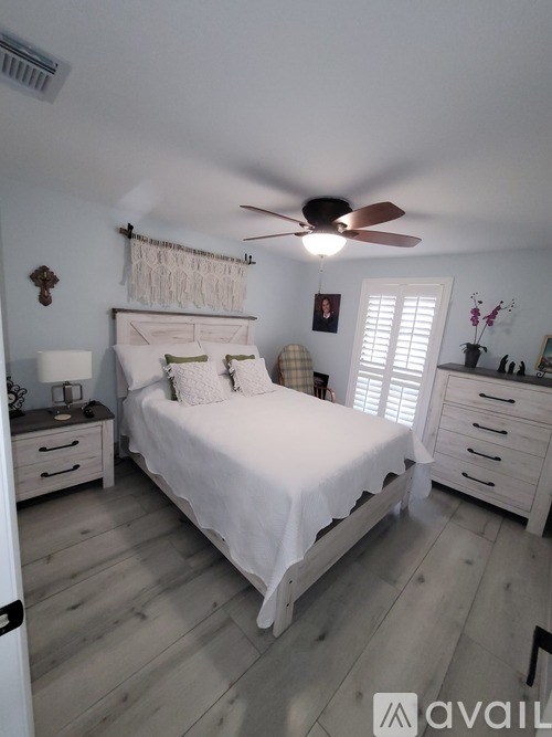 A bedroom with a bed, dresser, and ceiling fan.