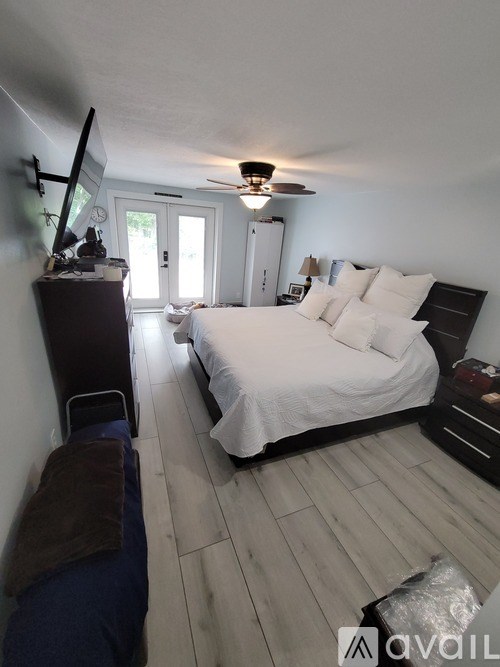 A bedroom with a bed, dresser, and ceiling fan.