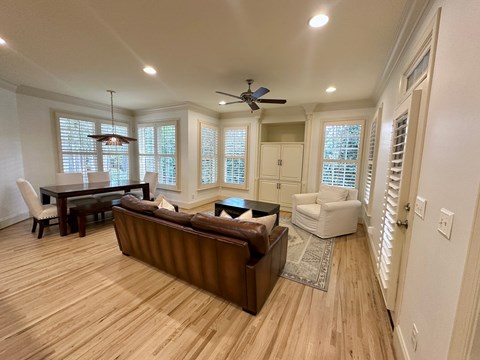 A living room with a brown couch and a ceiling fan.