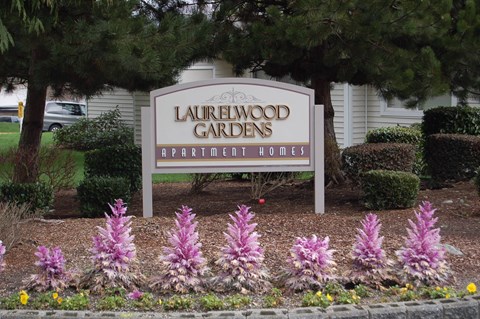 A sign for Laurelwood Gardens Apartment Homes is in front of a building.