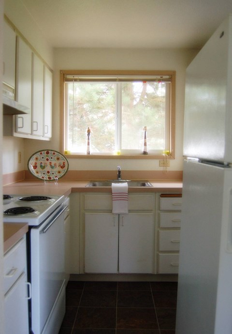 A kitchen with white appliances and a window.