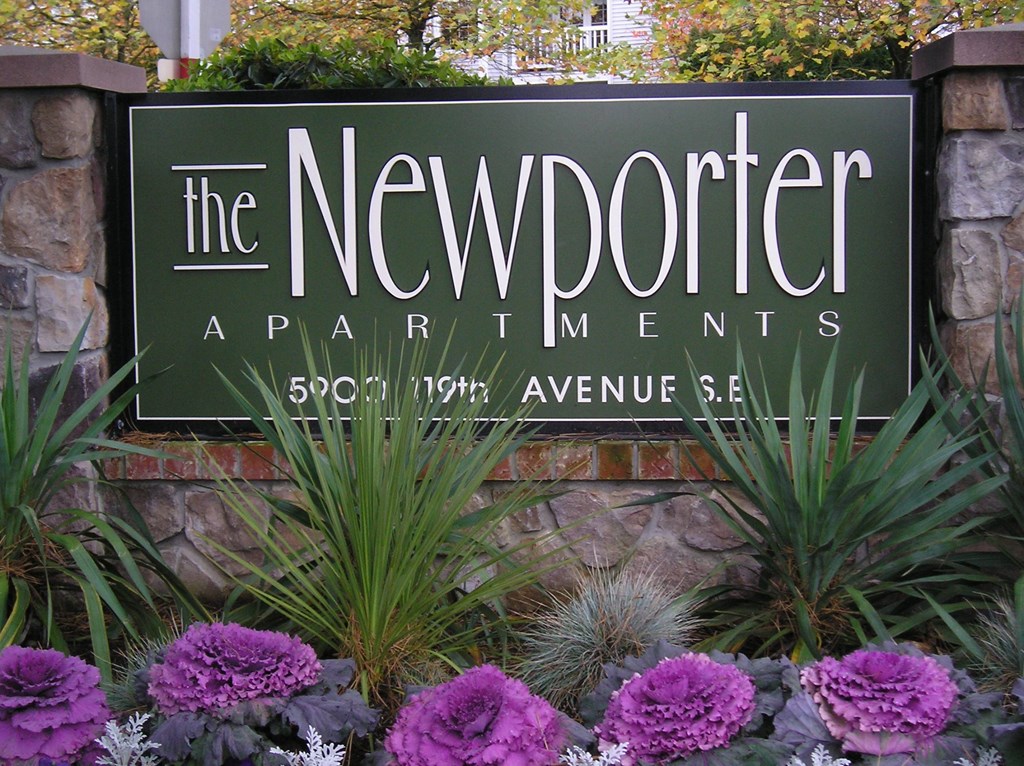 The Newporter Apartments sign is in front of a stone wall.