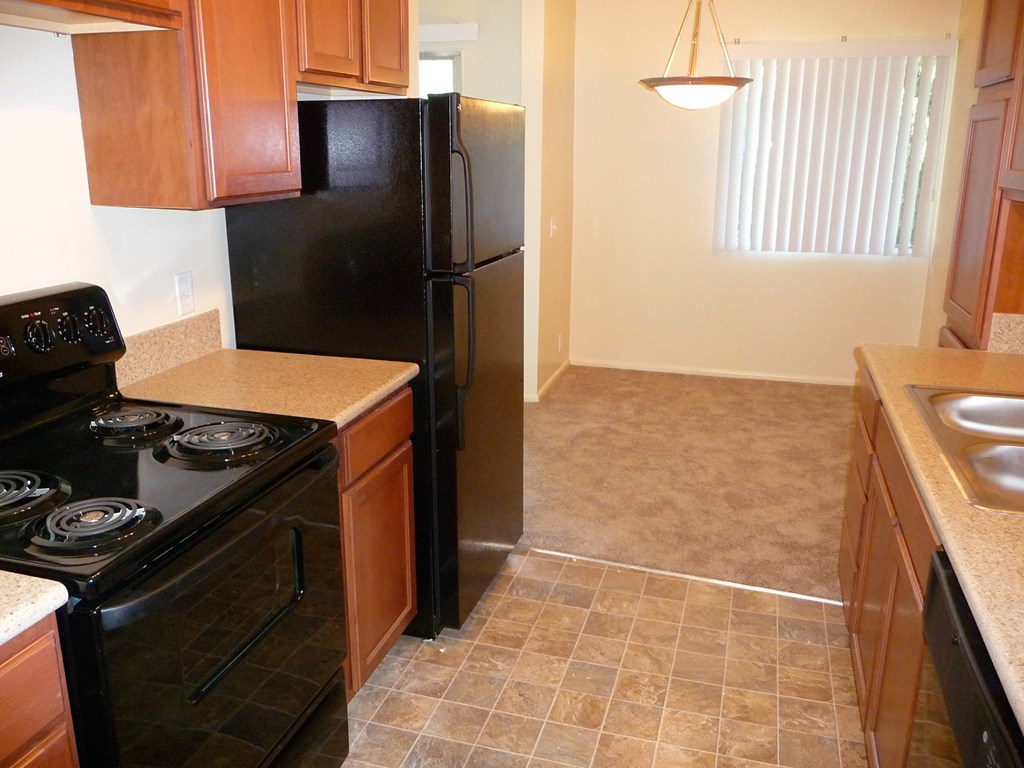 A kitchen with black appliances and brown cabinets.