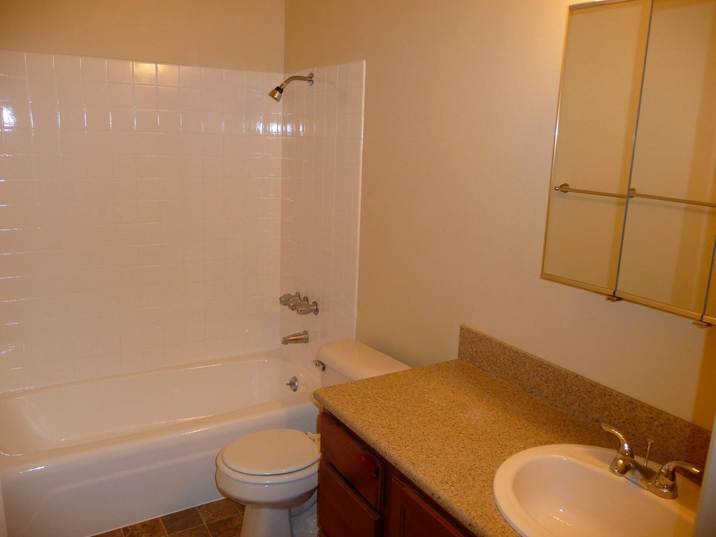 A white toilet sits next to a bathtub in a bathroom.