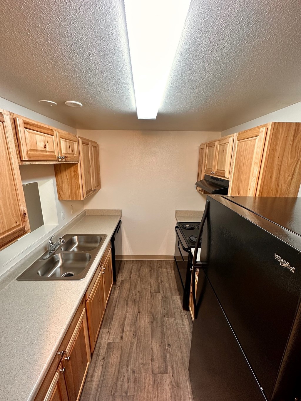 A kitchen with wooden cabinets and a black fridge.