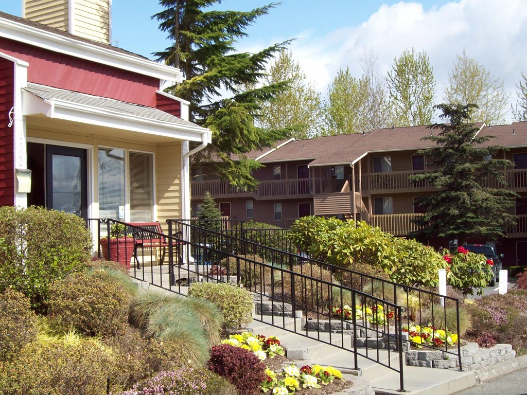 A red house with a white window and a black railing.