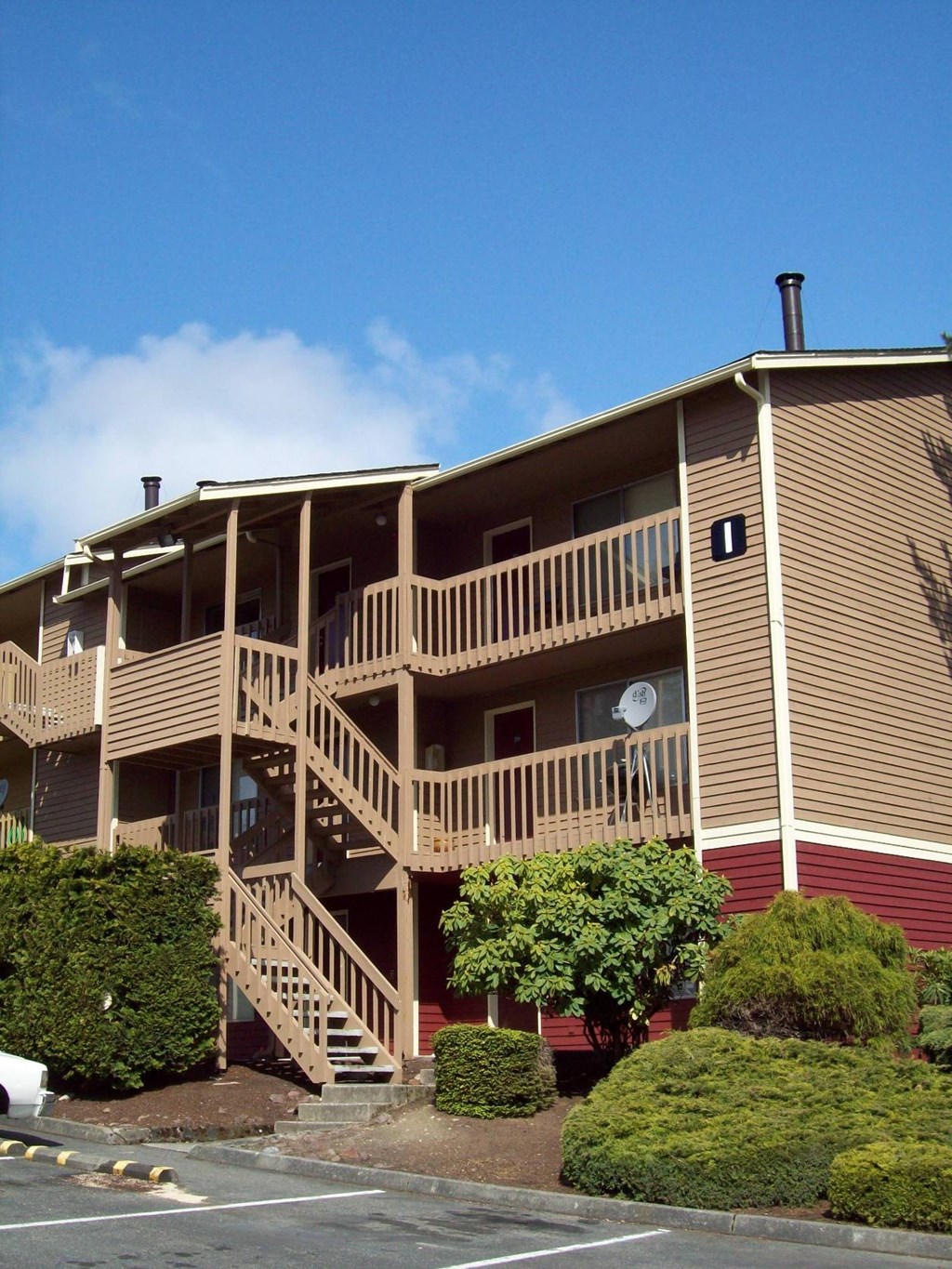A multi-story apartment building with a red exterior and a balcony on the second floor.
