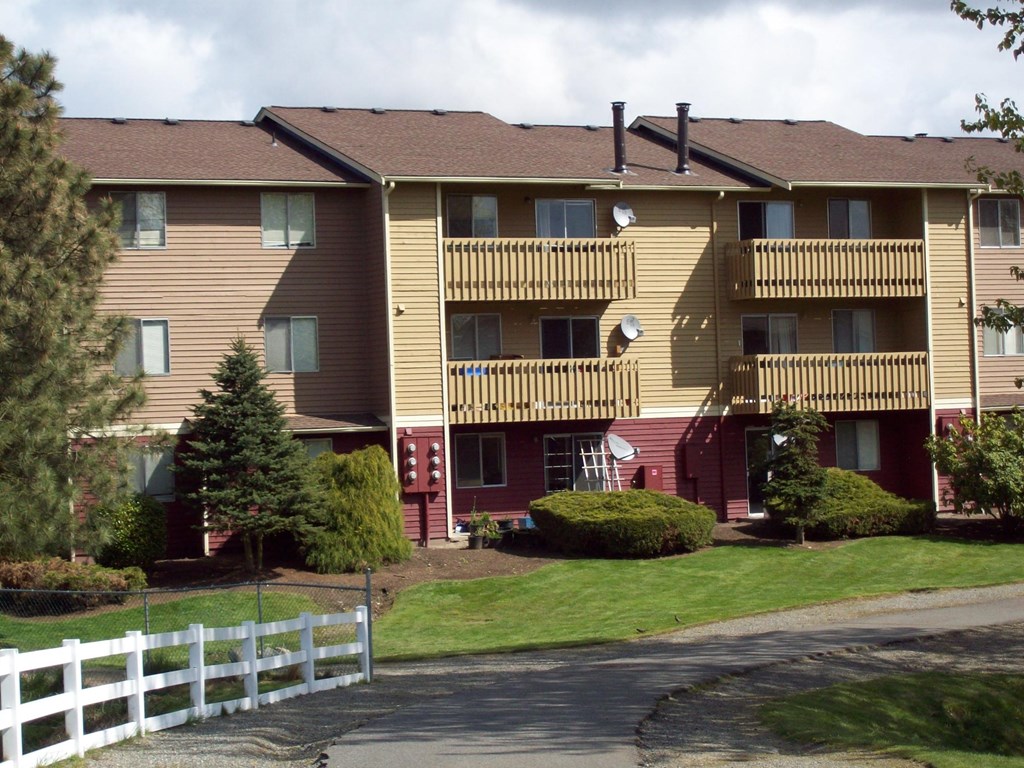 Apartment building with a white picket fence in front.