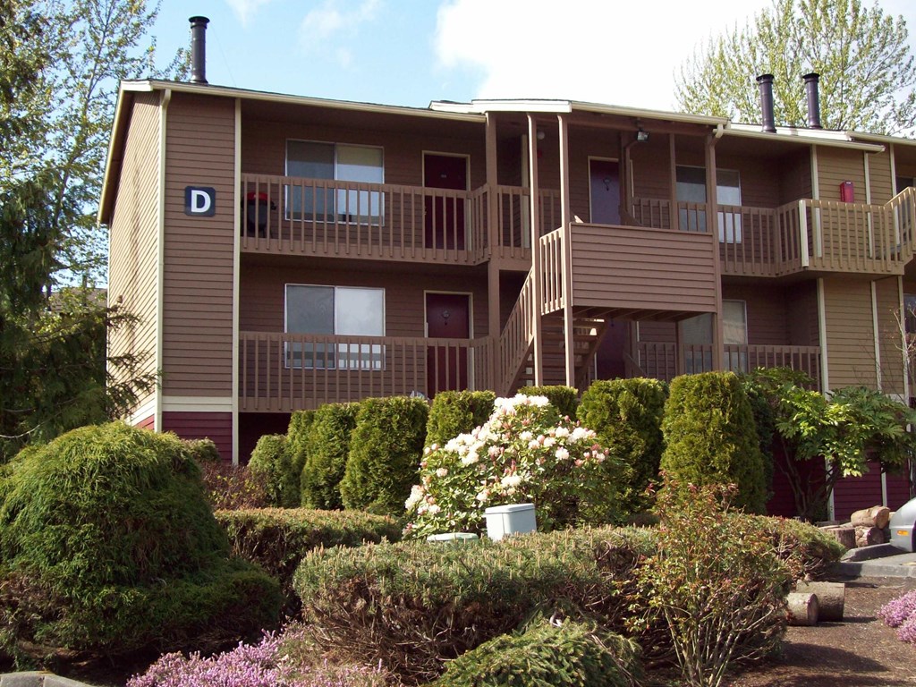 A building with a balcony and a garden in front.