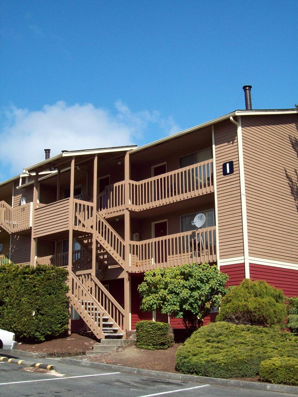 A multi-story apartment building with a red and beige exterior and a balcony on the second floor.