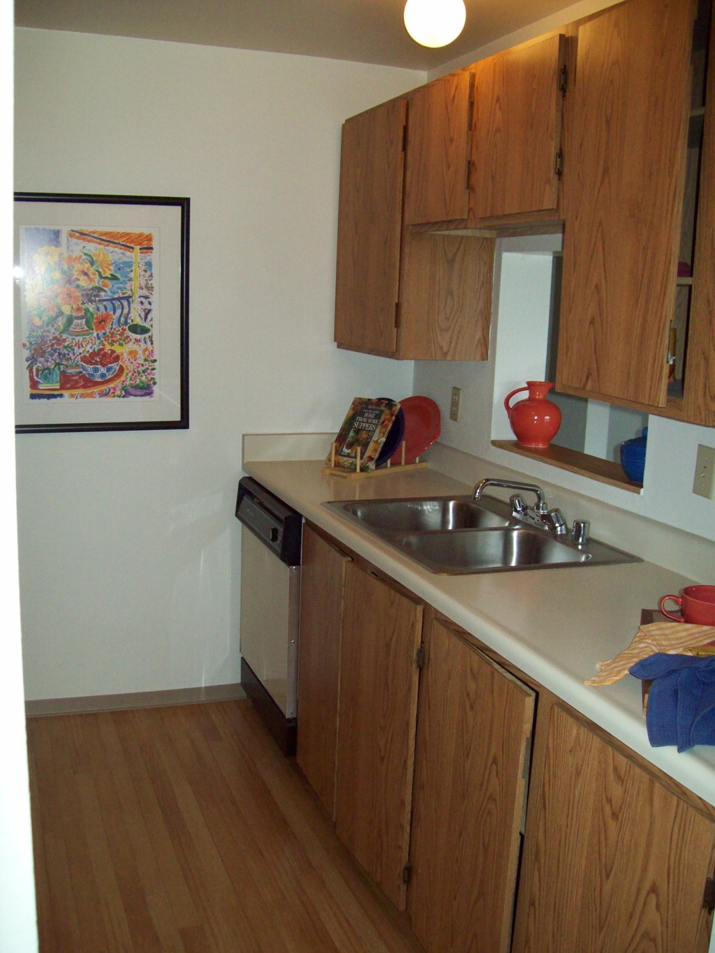 A kitchen with wooden cabinets and a framed picture on the wall.