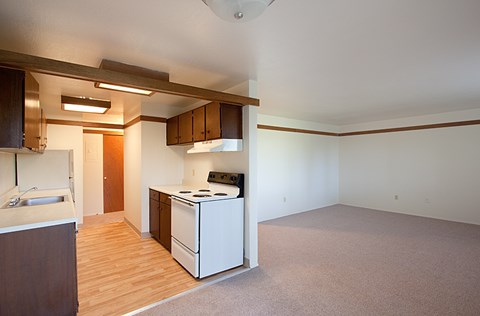 A kitchen with a white stove and wooden floors.