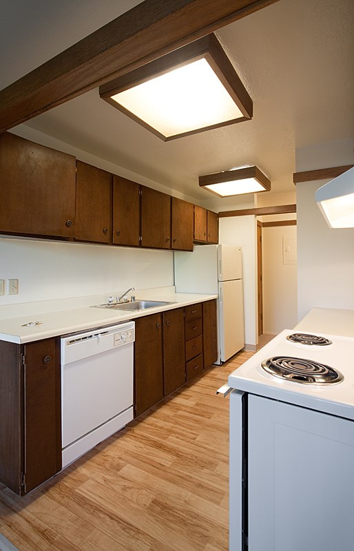 A kitchen with white appliances and wooden cabinets.