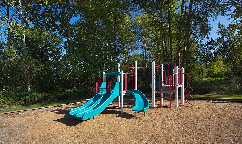 A playground with a red and blue slide and a red and white climbing frame.