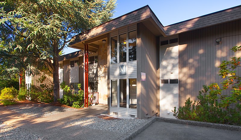 A modern house with a grey exterior and a red door.