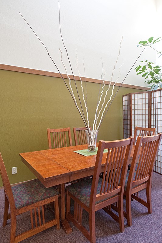 A wooden table with chairs and a vase with branches in it.