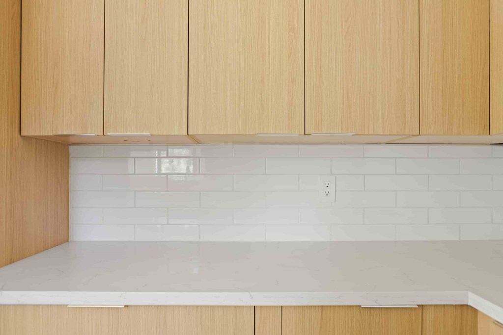A kitchen with wooden cabinets and white subway tiles.