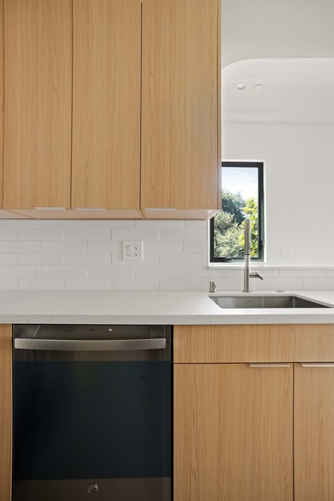 A kitchen with wooden cabinets and a black dishwasher.