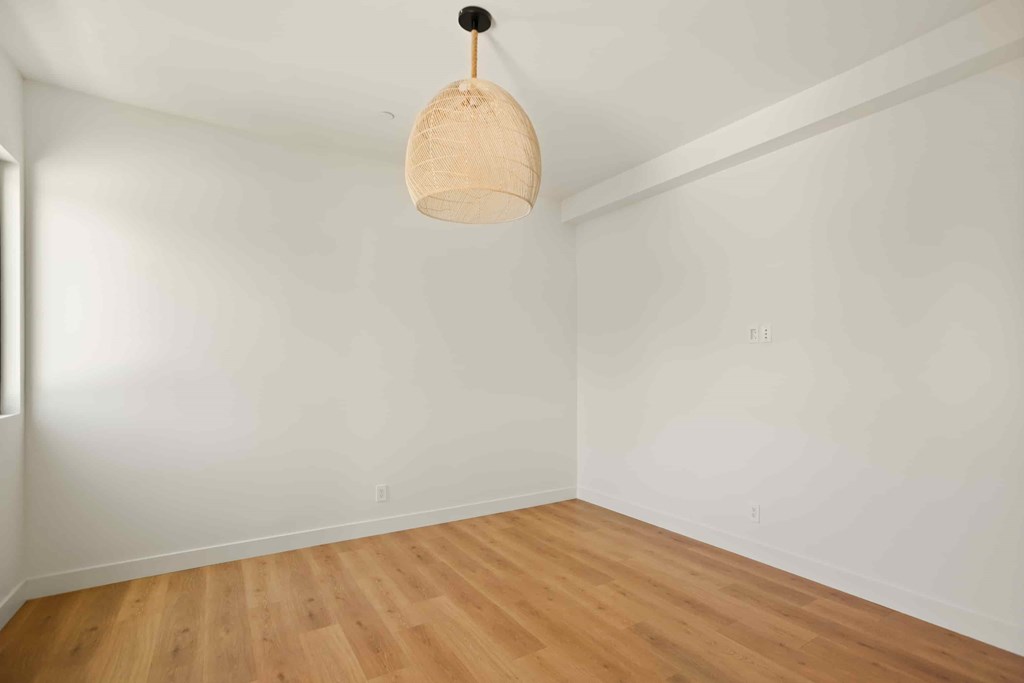 A room with a wooden floor and a hanging light fixture.
