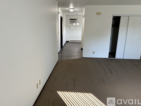 A long hallway with a white door on the right and a light on the ceiling.