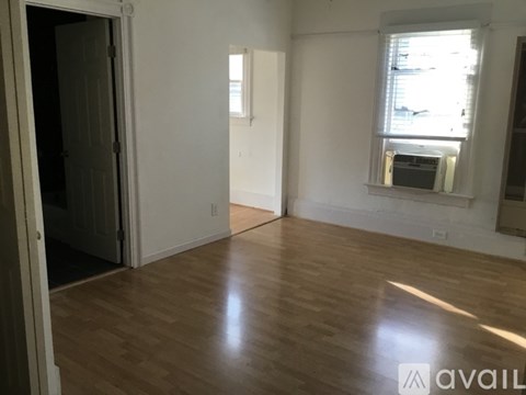 A room with wooden flooring and a window with blinds.