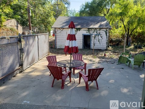 A patio with a table and chairs and a small white building in the background.