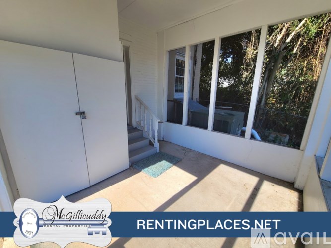 A room with a white door and a window with trees visible outside.