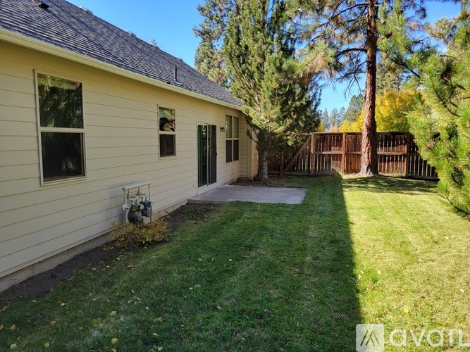 A house with a fence and trees in the background.