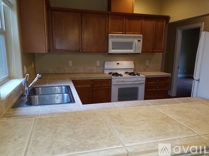 A kitchen with a stove, sink, and refrigerator.