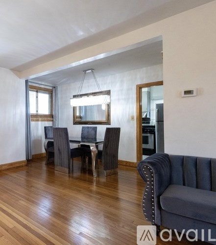 A living room with a grey couch and a dining table with chairs.