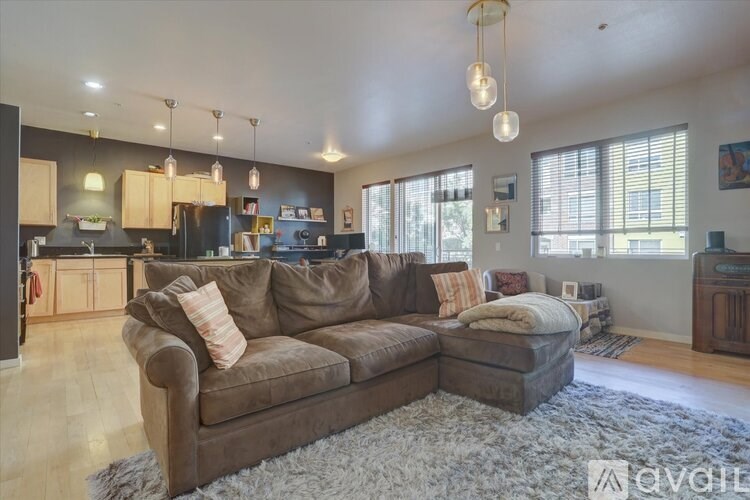 A living room with a brown couch and a white rug.