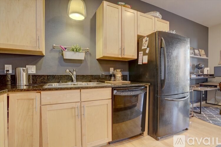 A kitchen with wooden cabinets and a black refrigerator.