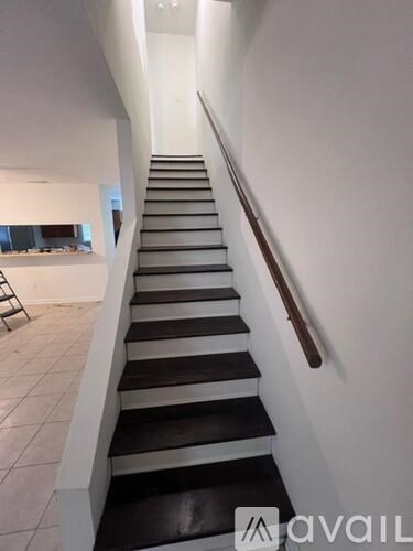 A staircase with black and white steps and a wooden handrail.