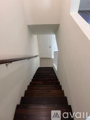 A long flight of wooden stairs leads to a white door.