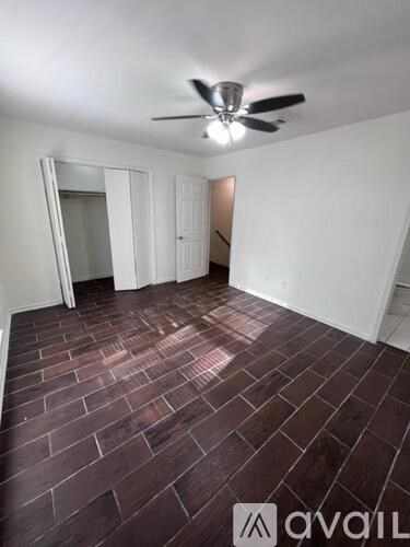 A room with a ceiling fan and brick flooring.