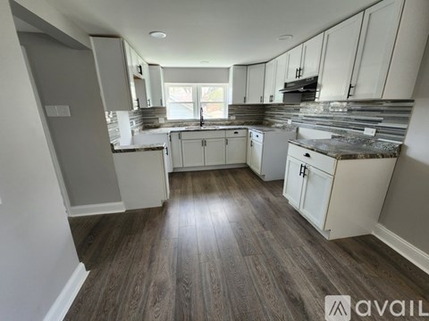 A kitchen with white cabinets and a wooden floor.