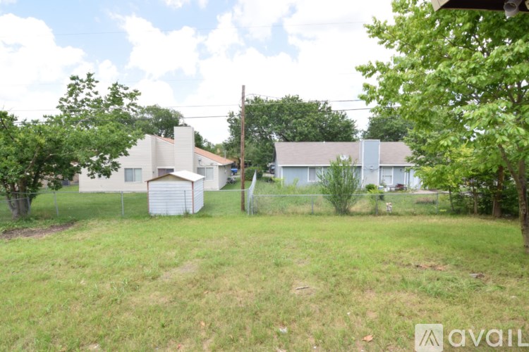 A grassy area with a house and trees in the background.
