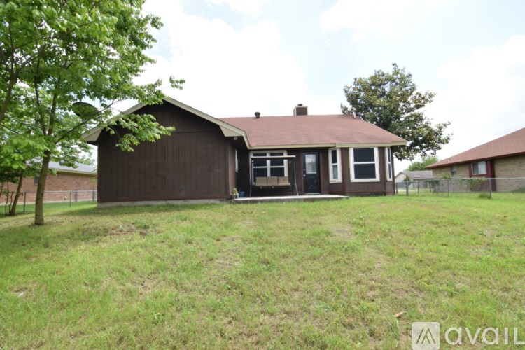 A house with a brown roof and a green lawn in front.