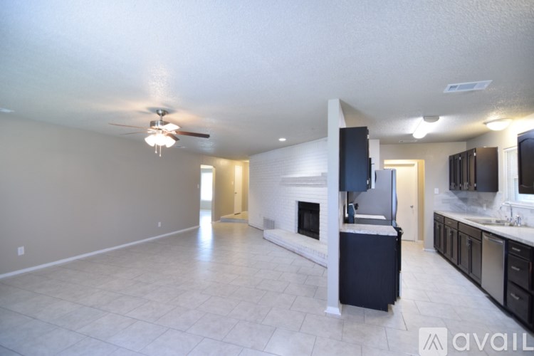 A spacious living room with a fireplace and a kitchen area in the background.