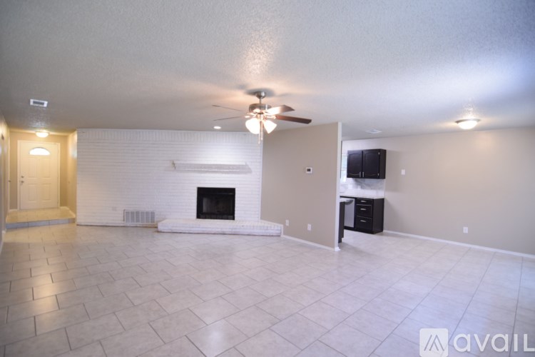 A spacious living room with a fireplace and a ceiling fan.