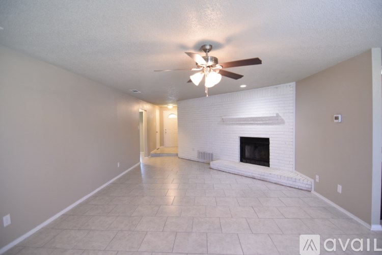 A spacious living room with a fireplace and a ceiling fan.
