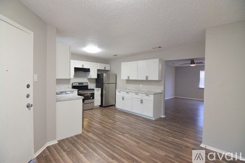 A kitchen with white cabinets and a wooden floor.