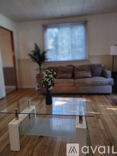 A glass table with a vase of flowers on it in a living room.