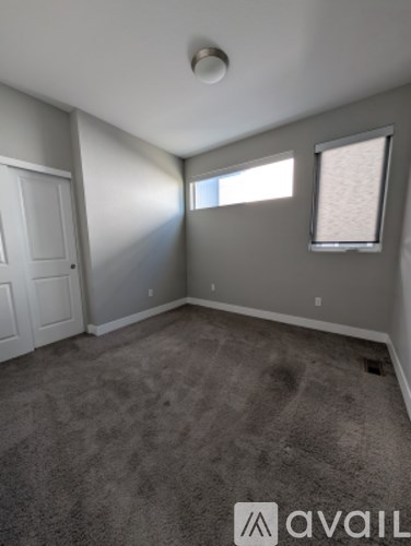 A room with a carpeted floor and a window with blinds.