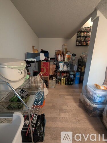 A kitchen pantry with a white fridge and a white chair.